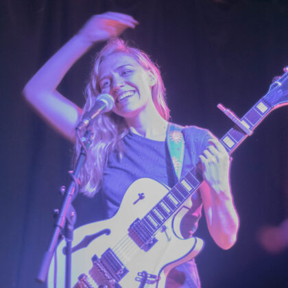 Female playing electric guitar, smiling