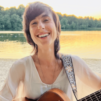 woman smiling with guitar outdoors