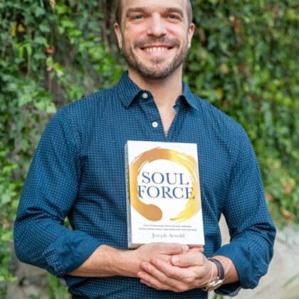 Joseph Arnold smiling, holding his book